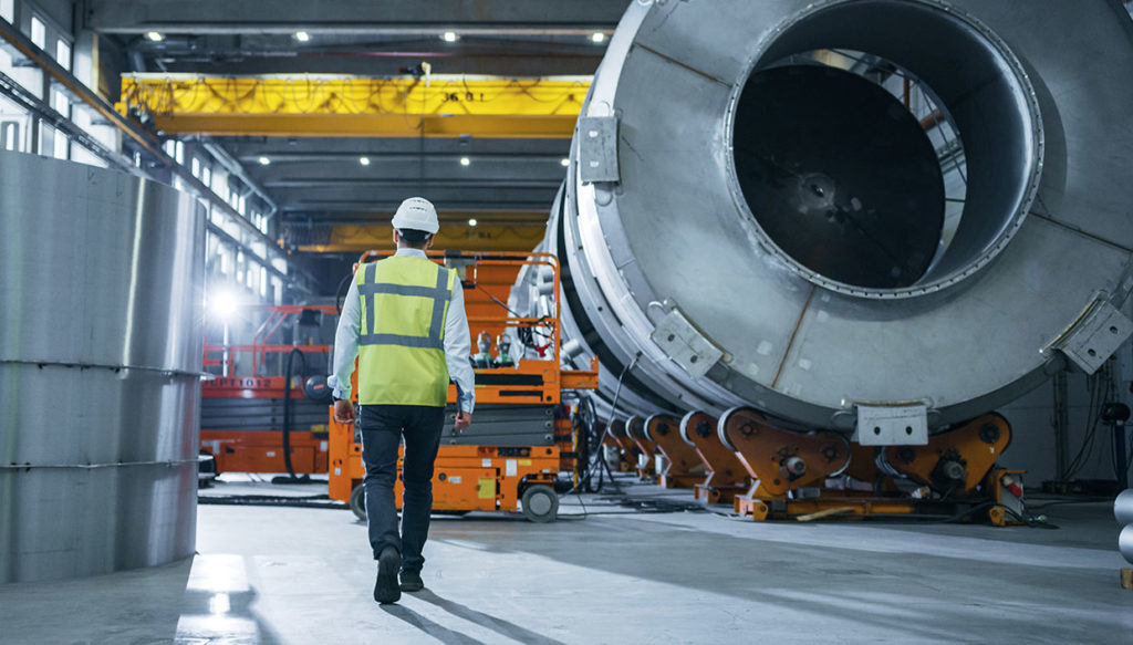 manufacturing worker in safety gear walking through a manufacturing facility