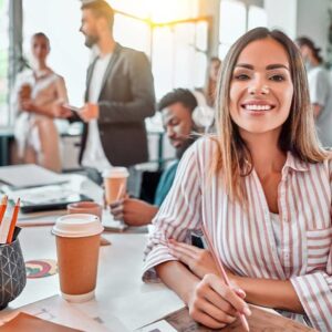 Professional Skills Business professional woman smiling sitting at a desk in a casual office setting.